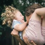 woman in pink sleeveless dress carrying baby in white shirt